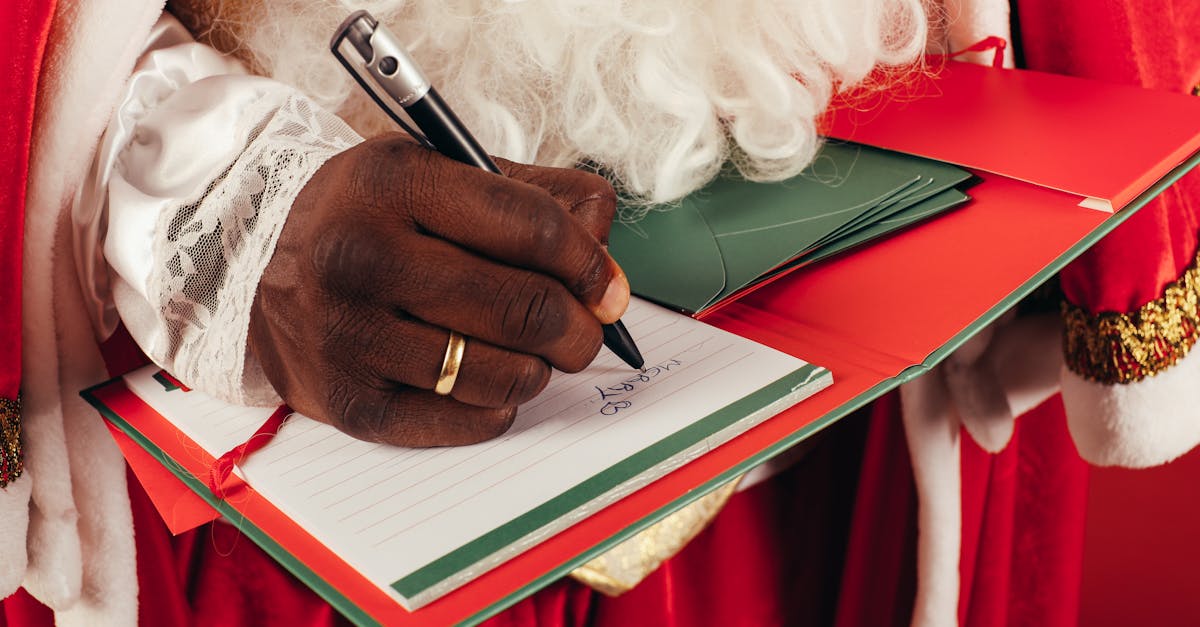 Close-up of Santa Claus writing a wishlist with a pen on a notepad. Festive holiday scene.