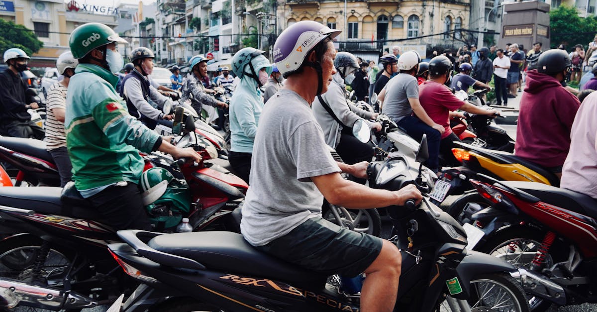 A busy urban street scene with numerous motorcyclists waiting at a traffic light.