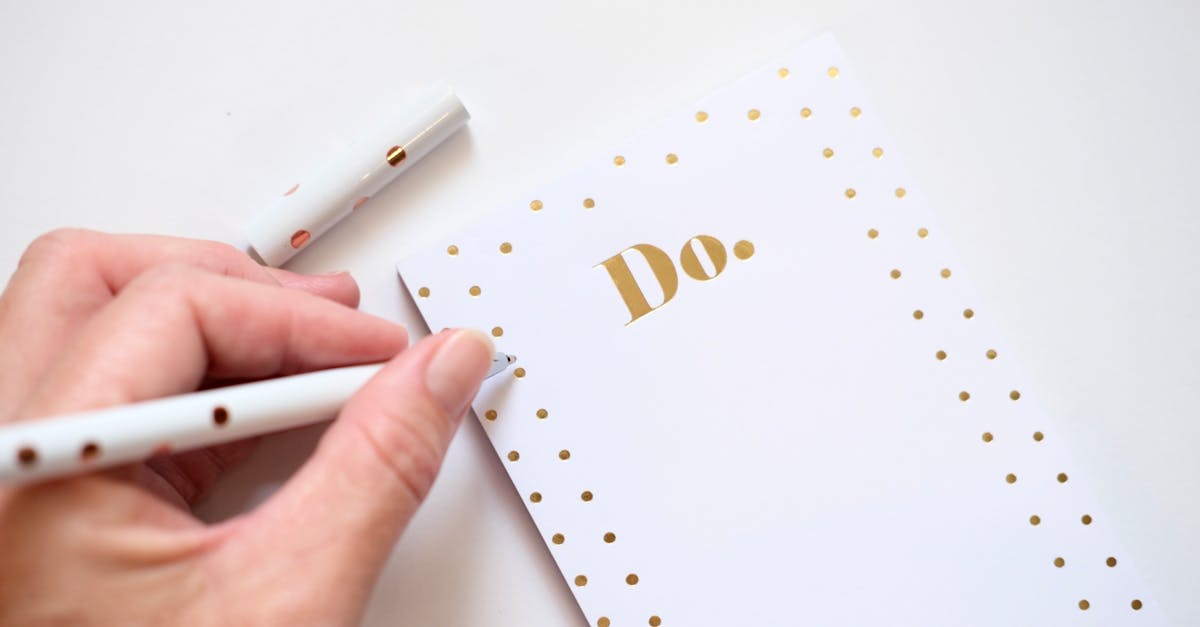 Hand schreibt mit Stift auf eine To-do-Liste.