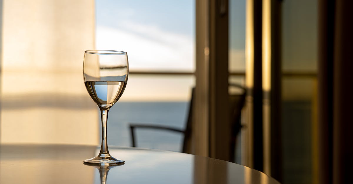 A glass of wine on a table with a stunning ocean view through a window, captured indoors.