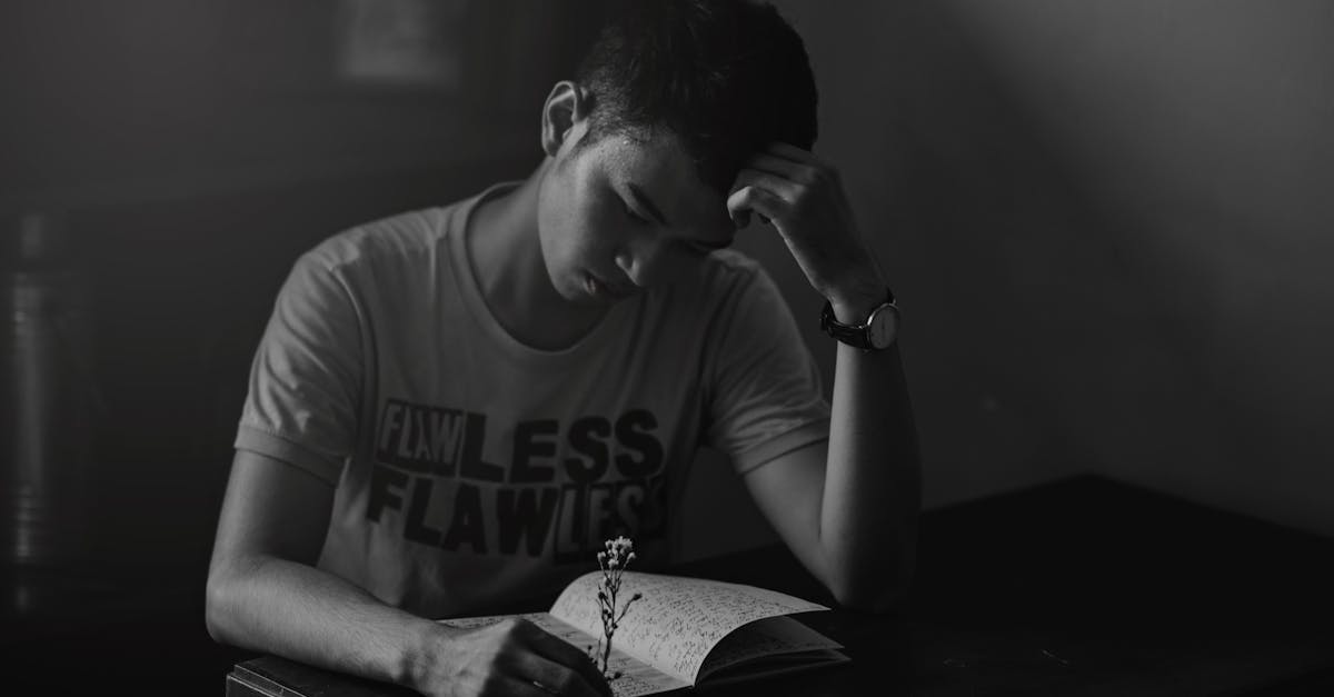 Contemplative young man reading a notebook in a dimly lit room.
