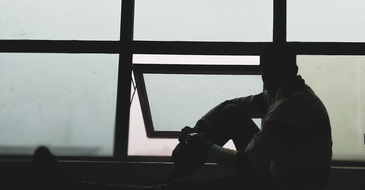 Shadowed silhouette of a person in thought next to a window, creating a mysterious and introspective atmospher