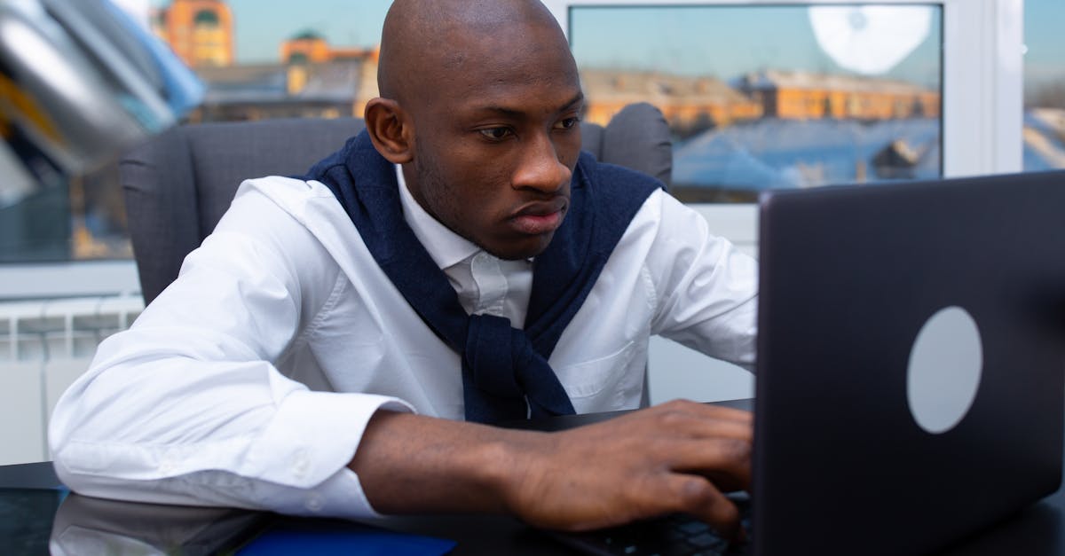Professional man working intently on his laptop in a modern office environment.