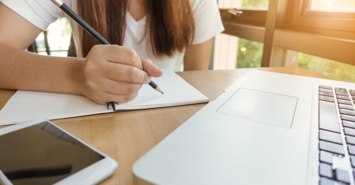 Closeup of crop anonymous lady with black manicure writing in planner with elegant pen