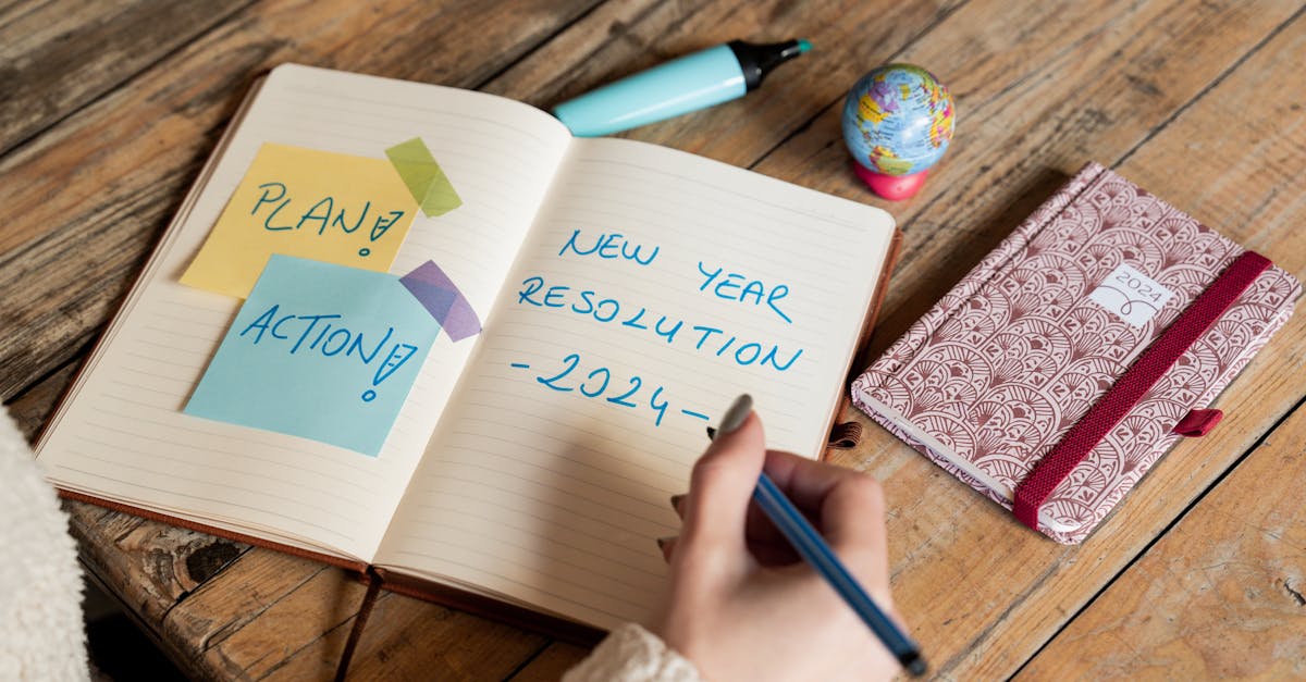 Person writing New Year 2024 resolutions in a notebook with sticky notes for planning and action.