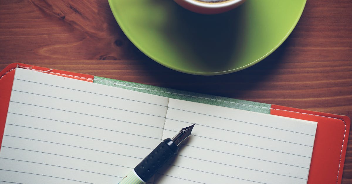 Tasse Kaffee, Fueller und offenes Notizbuch auf einem Holztisch.